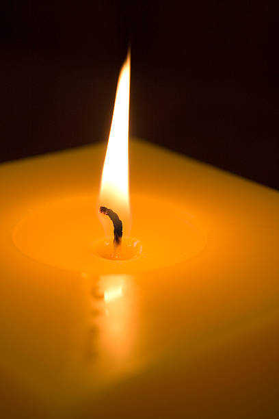 Candle light flame Close up of a square candle light with huge flame and nice reflection.  melting wax stock pictures, royalty-free photos & images