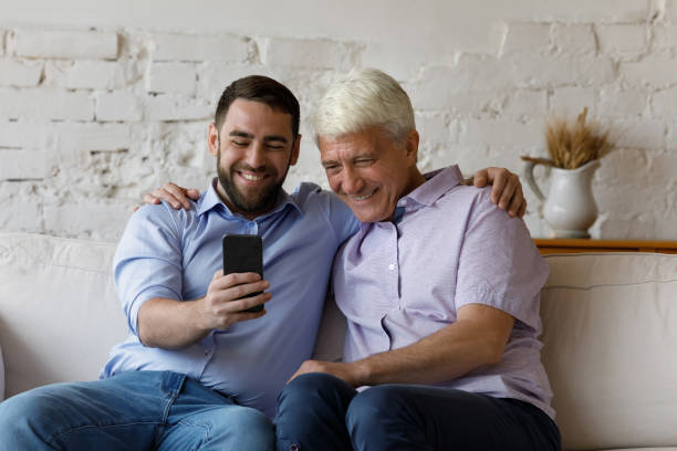 istock Cheerful grownup son and elder father taking selfie on smartphone 1379620843