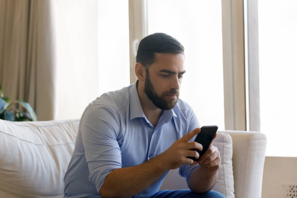 istock Focused millennial mobile phone user man chatting online 1379620910