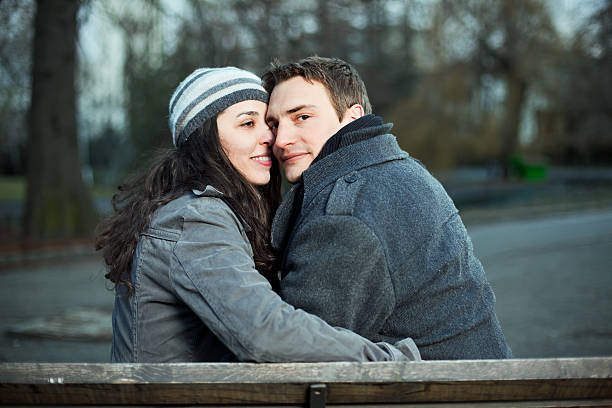 A young couple stands with their arms around each other and admires the sunset on the lake shore