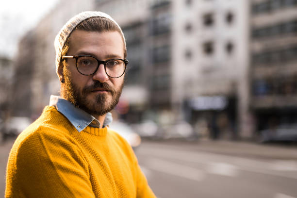 istock Hipster man looking at camera while standing on city street. 1379665980