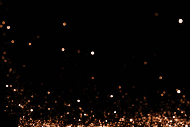 istock Blurred sparkles of gold color falling against black background 1379745286