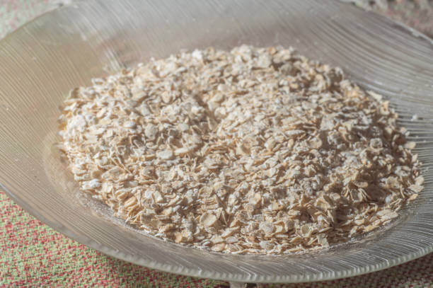Flaked oats, on a plate that is on a table with natural light,copy space in several parts.
