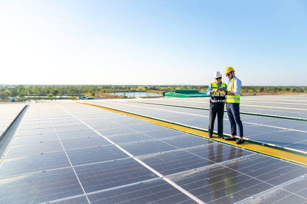 professional man engineer using digital tablet maintaining solar cell panels together on building rooftop. - solar power station solar panel energy electrician imagens e fotografias de stock