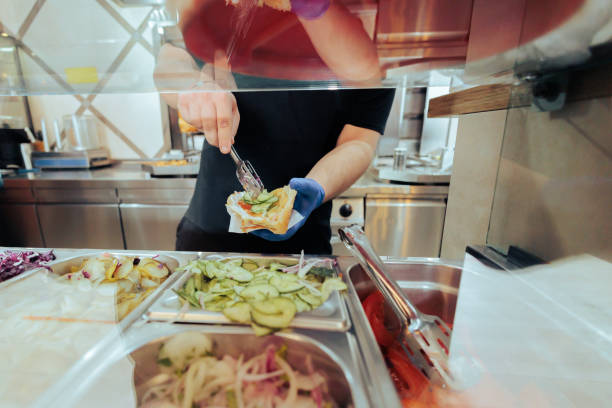 istock Cook Putting Sliced Cucumbers into a Sandwich 1379796664