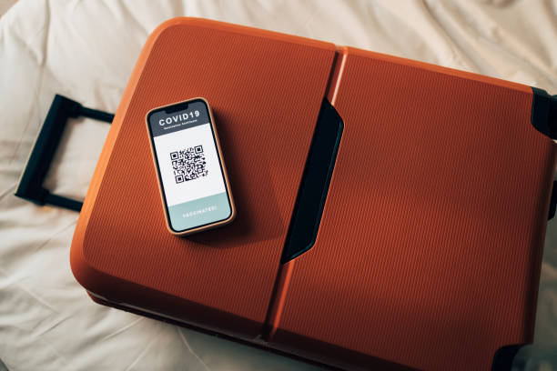 istock Getting Ready for Vacation: A Red Suitcase with a Smartphone Screen Showing a Covid Vaccination QR Code 1379812019