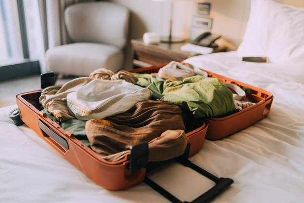 istock Packing the Essentials for Vacation: Open Suitcase Full of Clothes on a Bed with White Sheets 1379812036