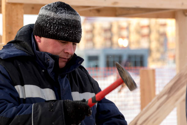 istock Worker in winter overalls with a hammer in his hand 1379855964