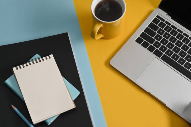 istock Top view notepad, computer laptop and coffee cup on colorful background. 1379912680