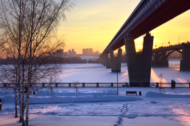 Novosibirsk, Siberia, Russia, 29.01.2022. Bridges on the winter embankment. The world's largest metro bridge across the Ob River covered with ice and snow in the evening