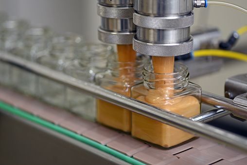 Jars of creamed honey in a packaging line at a commercial honey factory