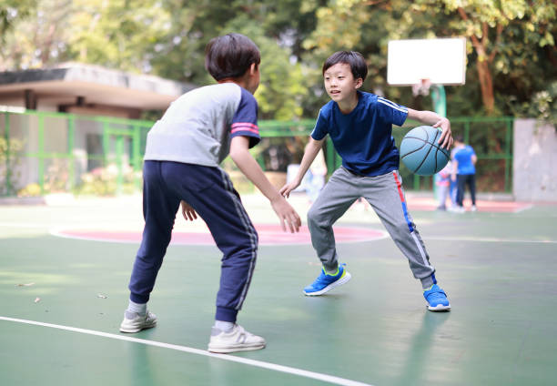 dois garotos jogando basquete do lado de fora - basketball child dribbling basketball player - fotografias e filmes do acervo