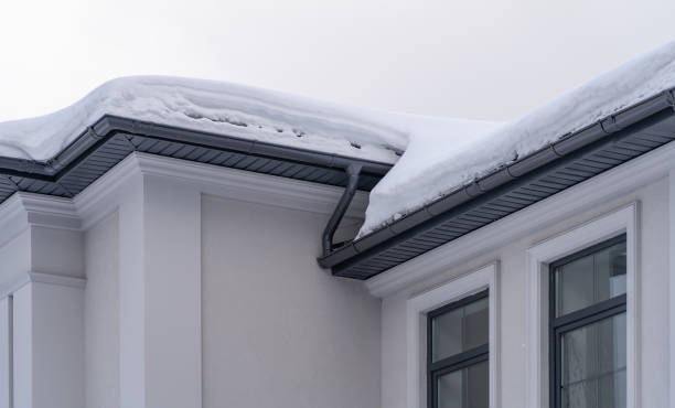 istock Metal Downpipe system, Guttering System, External downpipes and drainage pipes under snow. Corner of house with roof made of gray metal tiles and gutter covered with thick layer of snow in winter 1379951420