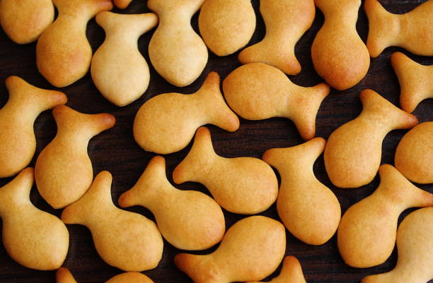 la texture est un petit craquelin fait de biscuits en forme de poisson. - poisson rouge photos et images de collection