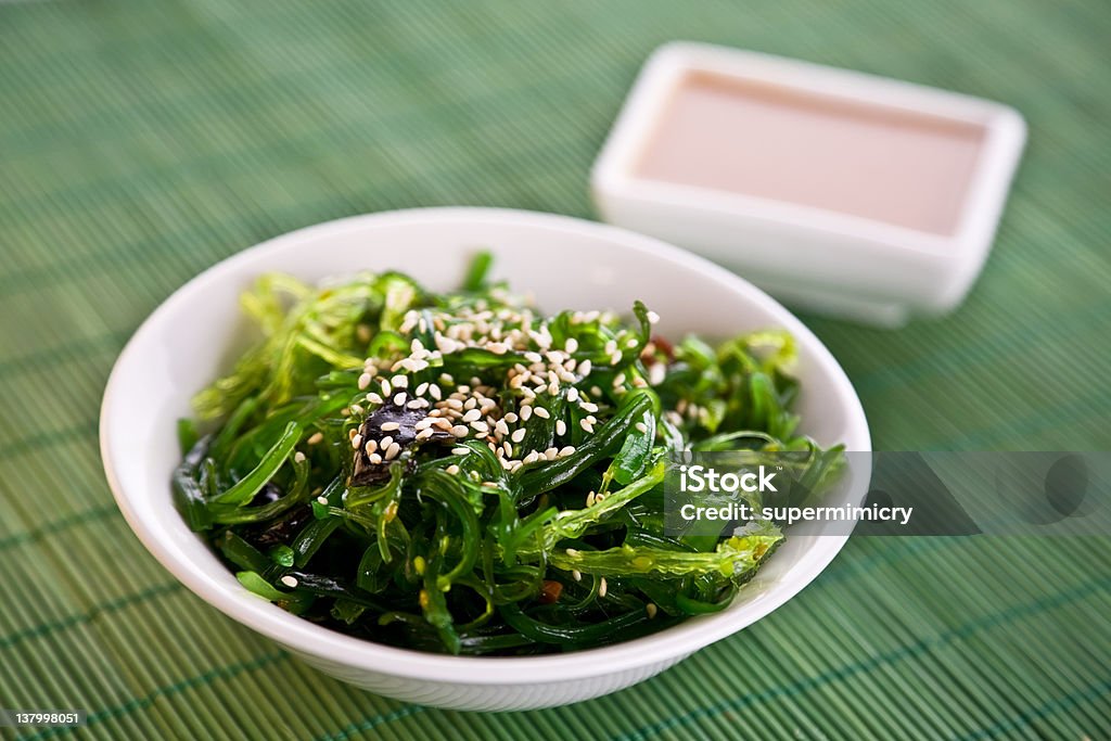A bowl of Wakame seaweed salad Wakame seaweed salad with nut sauce, garnished with sesame seeds and red chili pepper Seaweed Stock Photo