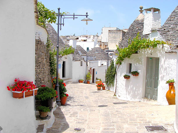 Alberobello Trulli houses with flowers Pretty street among the unique trulli houses of Alberobello, Italy trulli house photos stock pictures, royalty-free photos & images