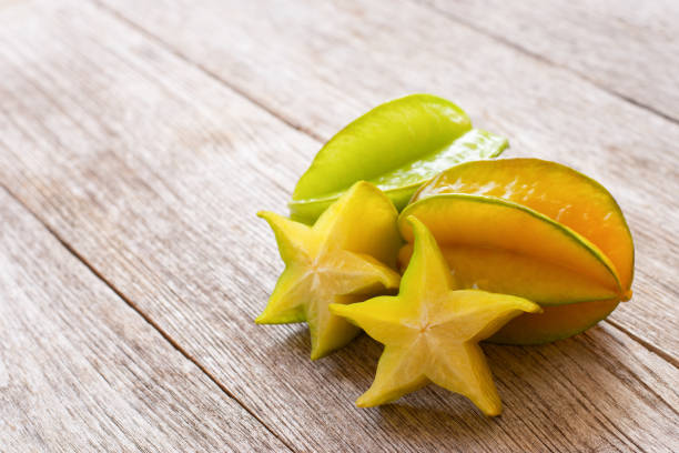 świeży owoc karamboli (starfruit, star apple) z plastrami na drewnianym stole - starfruit zdjęcia i obrazy z banku zdjęć