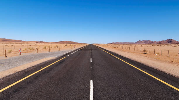 vista de baixo ângulo da estrada na república da áfrica do sul para a namíbia - arid climate asphalt barren blue - fotografias e filmes do acervo