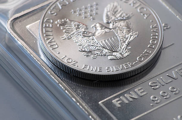 Silver Coin Bullion Silver Coin Bullion 1 ounce on top of a larger bullion bar, precious metal investments. precious metals stock pictures, royalty-free photos & images