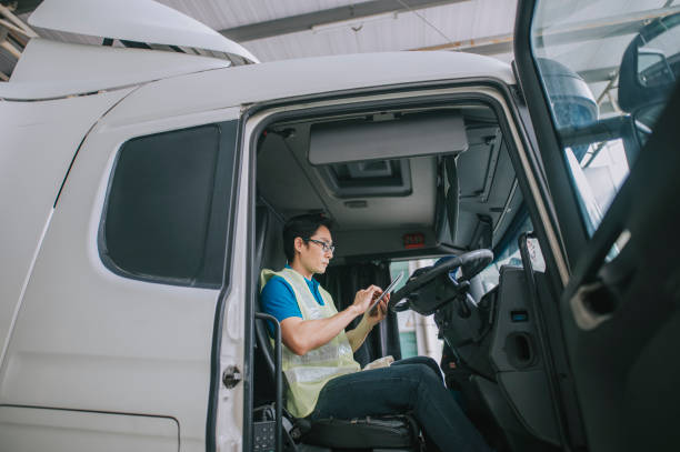 asiatisch-chinesischer sattelschlepperfahrer mit digitalem tablet, der die lieferplanliste aktualisiert - computer manual worker truck driver truck stock-fotos und bilder