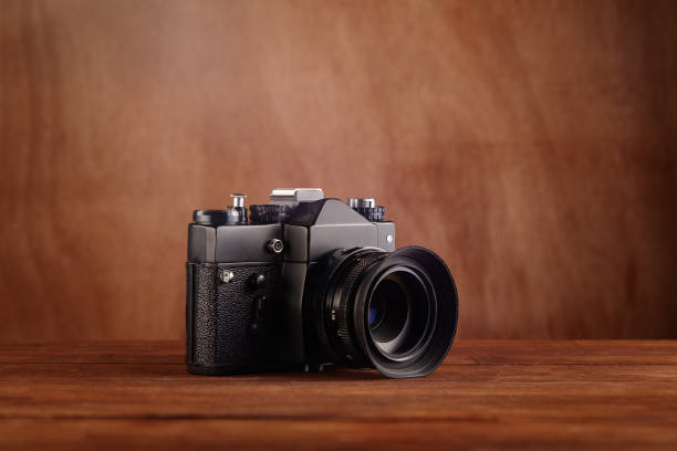 istock SLR Single-lens reflex professional camera on wooden table and background 1380025826