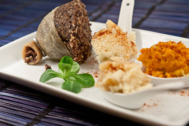 Haggis,neeps and tatties Haggis and turnip and potato mash and sweet potato mash presented in a plate with a cooked half haggis and a lamb's leaf lettuce, traditional food of Scotland presented in a modern way haggis stock pictures, royalty-free photos & images