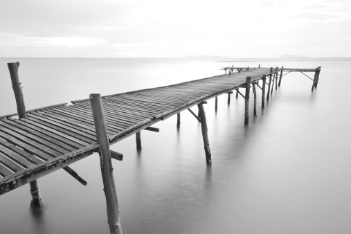 black and white picture of old bridge to the sea with long exposure technique.