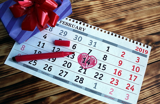 on the table lies a calendar with a circled number 14 February with a gift box.on the table lies a calendar with a circled number 14 February with a gift box.