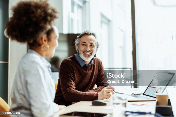 Smiling Financial Advisor And Business Person Talking To Mixed Race Female Colleague In Office Stock Photo - Download Image Now