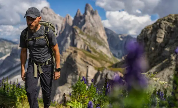 Outdoors iconic landscape on the Dolomites: the Seceda famous landmark. A man hiking alone in the majestic landscape