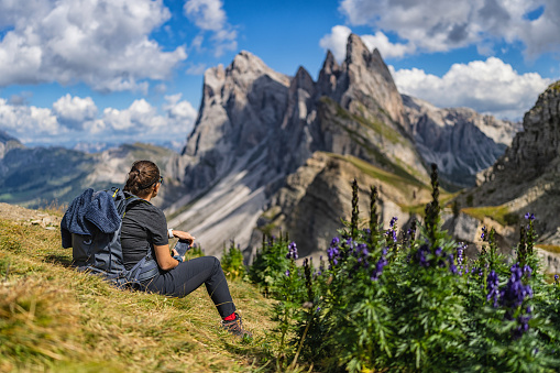 Outdoors iconic landscape on the Dolomites: the Seceda famous landmark. A woman hiking alone in the majestic landscape