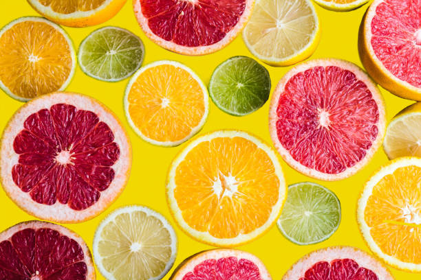 limões coloridos diferentes em um fundo amarelo - citrus fruit - fotografias e filmes do acervo