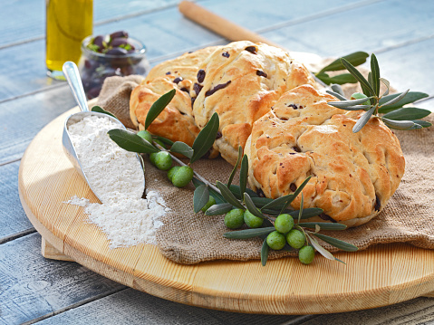 delicious homemade traditional olive bread, served on a wooden dish,made from premium ingredients,organic products like olives,olive oil,flour.