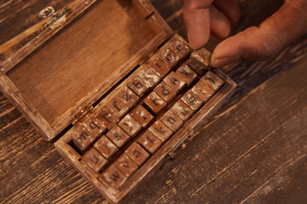 Cropped photo of hand taking alphabet stamp out of open wooden box on table