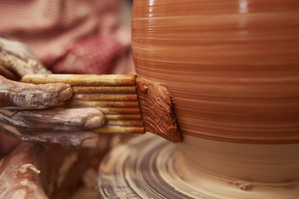 istock Skilled ceramist painting earthenware vessel with glaze 1380116012