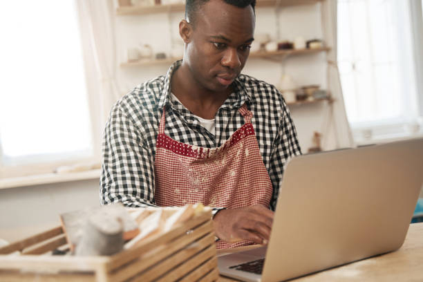 istock Cheerful ceramist watching something on his portable computer 1380116033