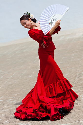 Woman traditional Spanish Flamenco dancer dancing in a red dress with a white fan
