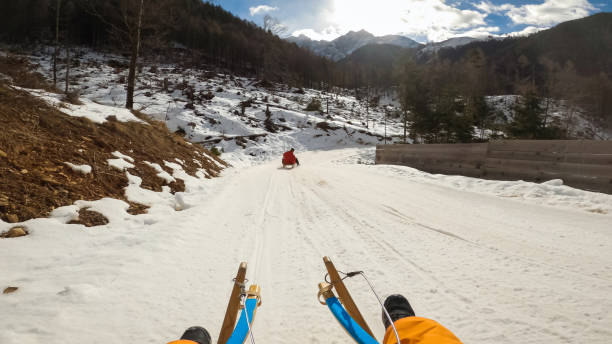 Senior couple relaxing on sled and admiring beautiful mountain view from snowy winter landscape