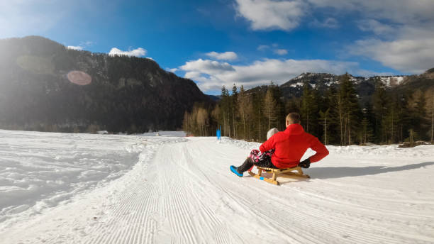 Family sledding on the snow and having fun in winter.