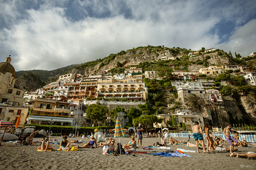 Positano, Italy, June 11, 2011: A summer day on the beach, with people tanning under the sun on the beach in front of the small town, on June 6, 2011 in Positano, Italy. Positano in one of the many wonderful towns of the Amalfi coast, on Penisola Sorrentina.