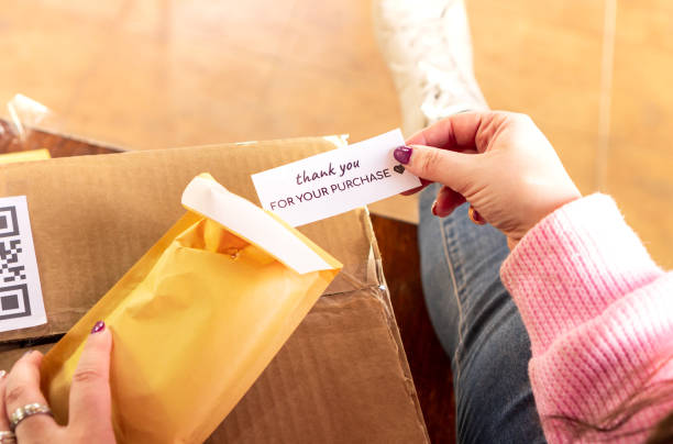 istock High angle of crop anonymous female sender packing order in envelope and putting note thank you for purchase before shipping in box 1380153813