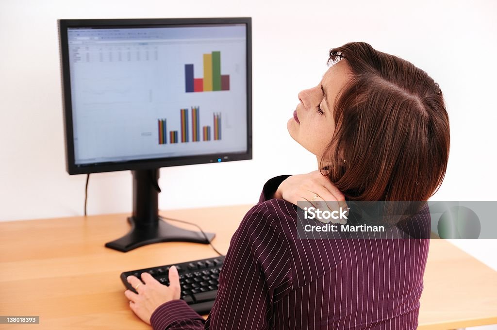 Business woman with neck pain Business woman with neck pain. Focus on hand on neck with blurred monitor on table in background. Backache Stock Photo