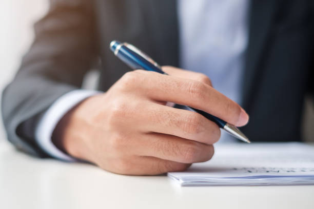 istock man signing on contract documents after reading, man holding pen and approve on business report. Contract agreement, law and deal concepts 1380191571