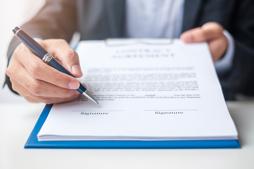 Businessman signing on contract documents after reading, man holding pen and approve on business report. Contract agreement, partnership and deal concepts