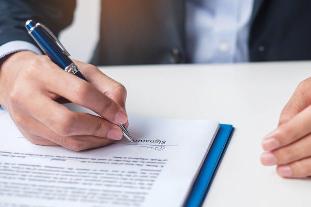 istock man signing on contract documents after reading, man holding pen and approve on business report. Contract agreement, law and deal concepts 1380195830