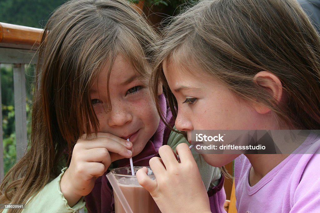 Twin brunette ragazze, bere cioccolata attraverso le cannule - Foto stock royalty-free di Bambino