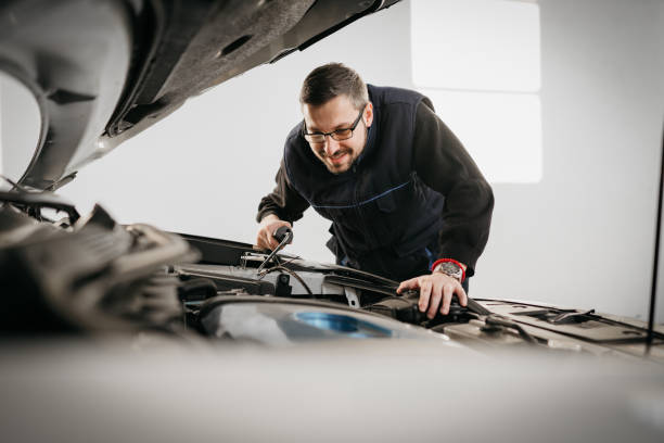 istock Auto mechanic opening radiator cap while repairing car in a repair workshop 1380258955