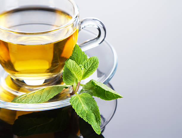 istock Yellow colored tea in a clear cup on saucer with fresh mint 138026501