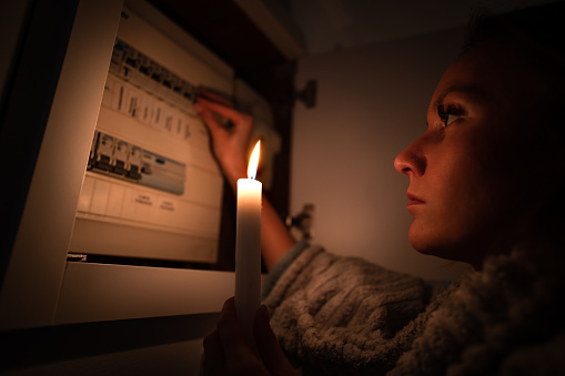 Woman checking fuse box at home during power outage or blackout. No electricity concept. High quality photo