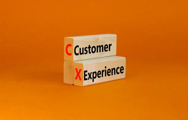 Photo of CX customer experience symbol. Concept words CX customer experience on wooden blocks on beautiful orange table orange background, copy space. Business and CX customer experience concept.
